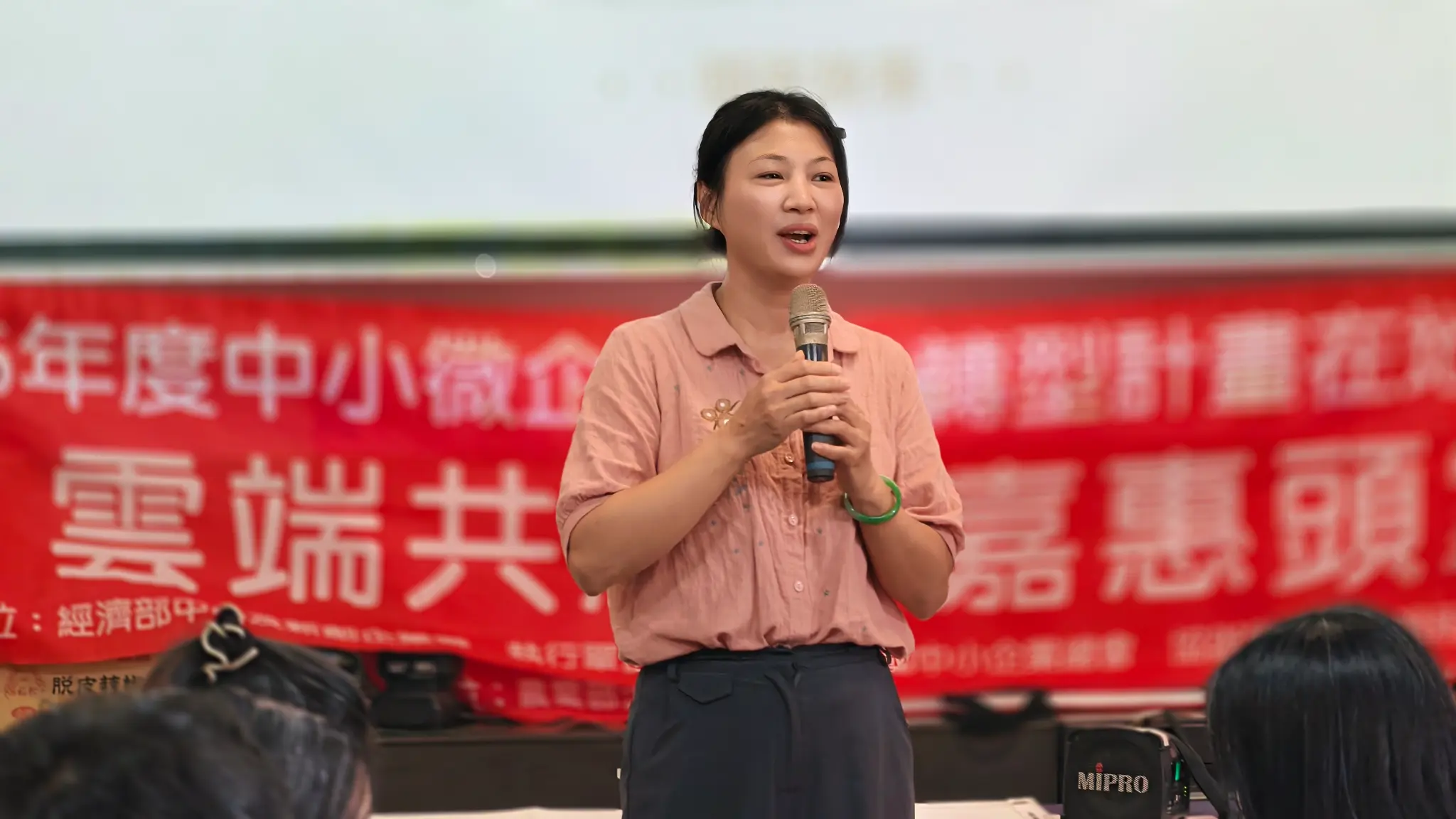 台灣新住民產業協會理事長張艷君於成果發表會持麥克風發言